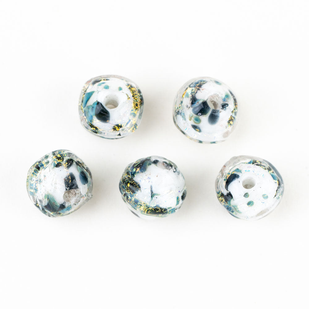 Five glass beads from Unicorne Beads featuring a white base color with dark blue and dichroic accents. Each bead is hollow with openings on each side to be used for jewelry making. 