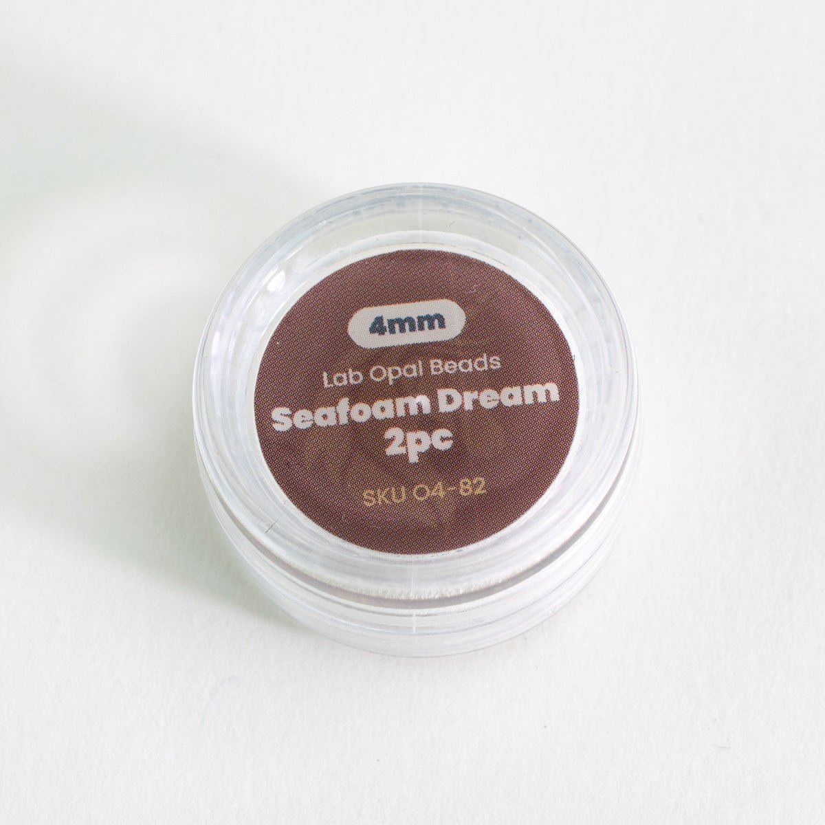 Container of lab opal beads labeled 'Seafoam Dream' on a white background