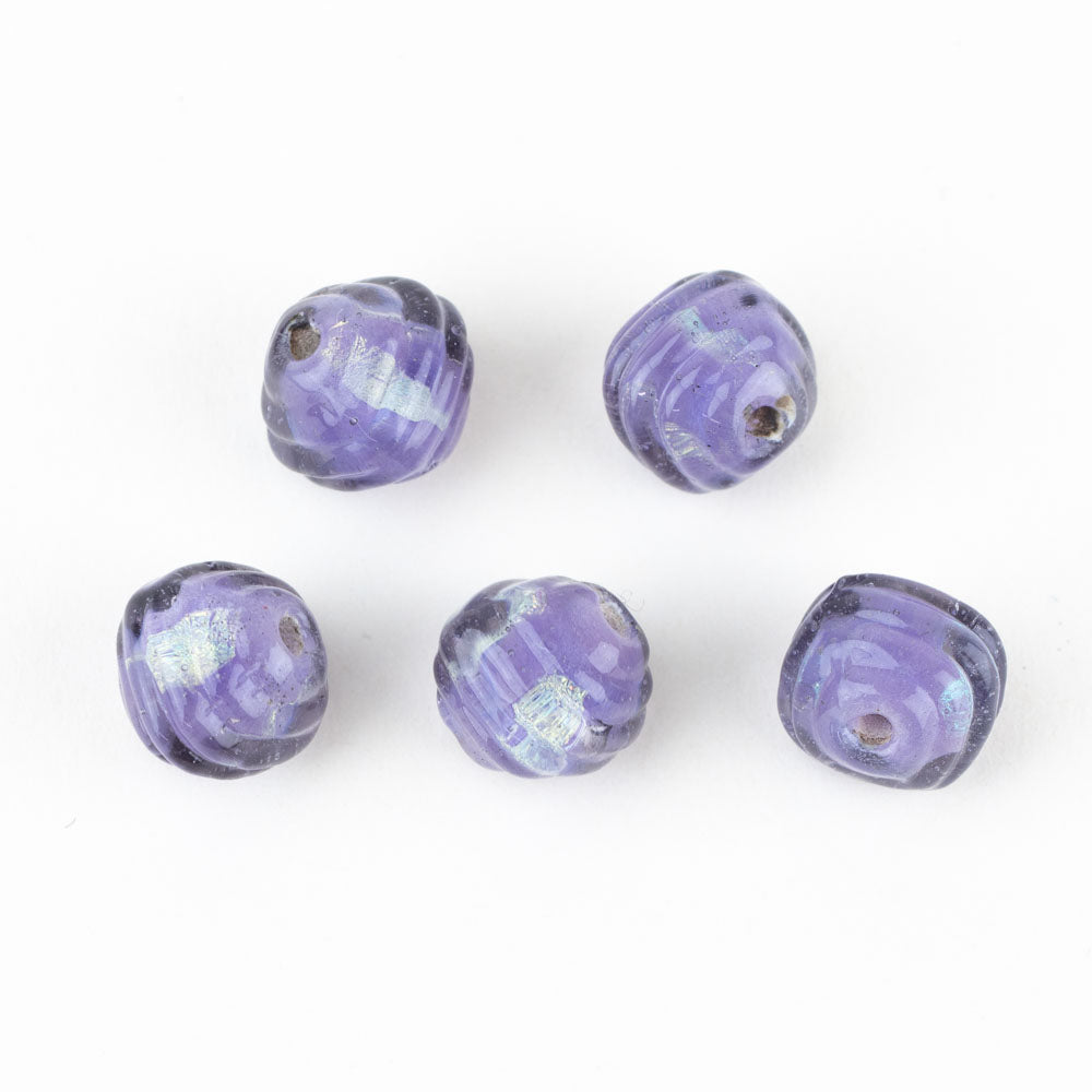 Five coconut glass beads from Unicorne Beads, made from purple glass with dichroic coloring. Each bead has two holes in them to be used from jewelry projects.