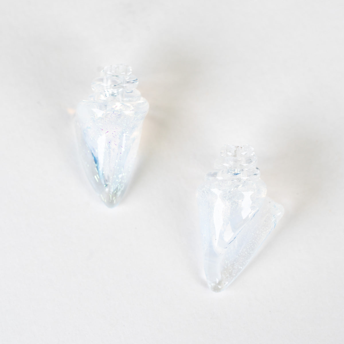Two clear seashell-shaped beads on a light white background