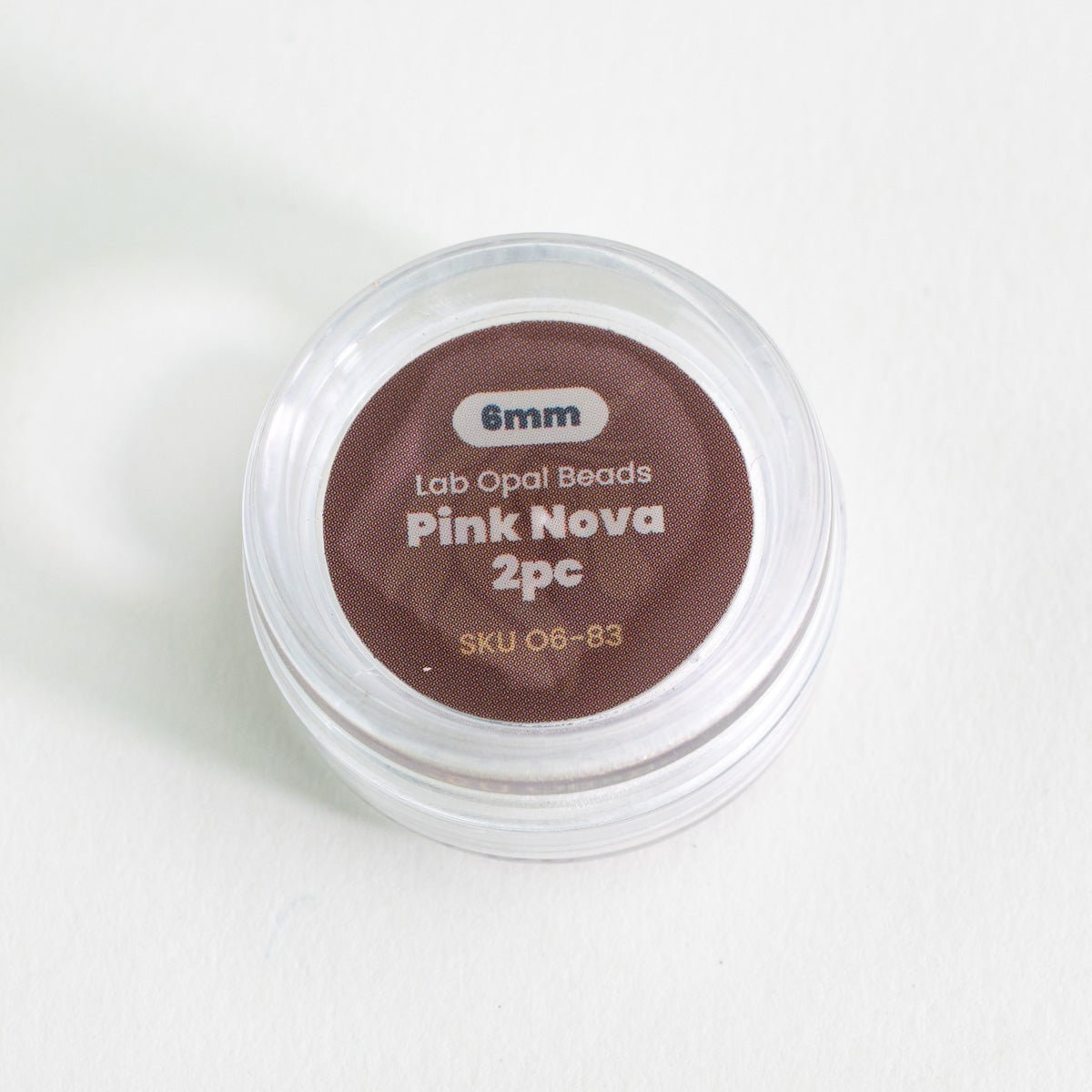 Container of pink lab opal beads with label on a white background