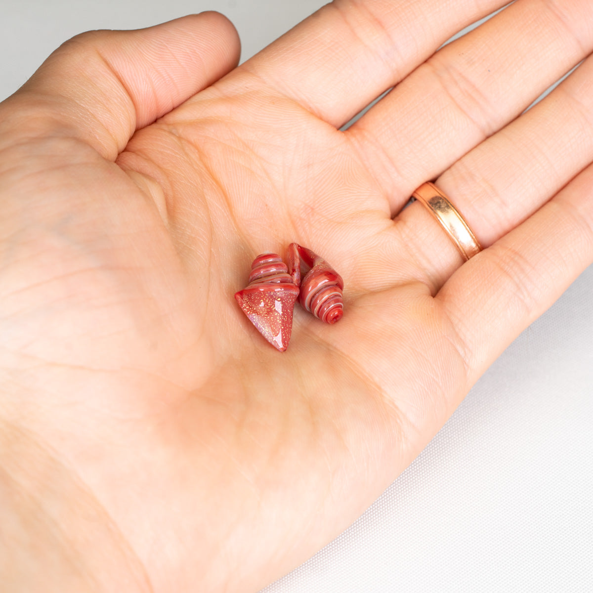 Customizable red seashell beads on palm with white background