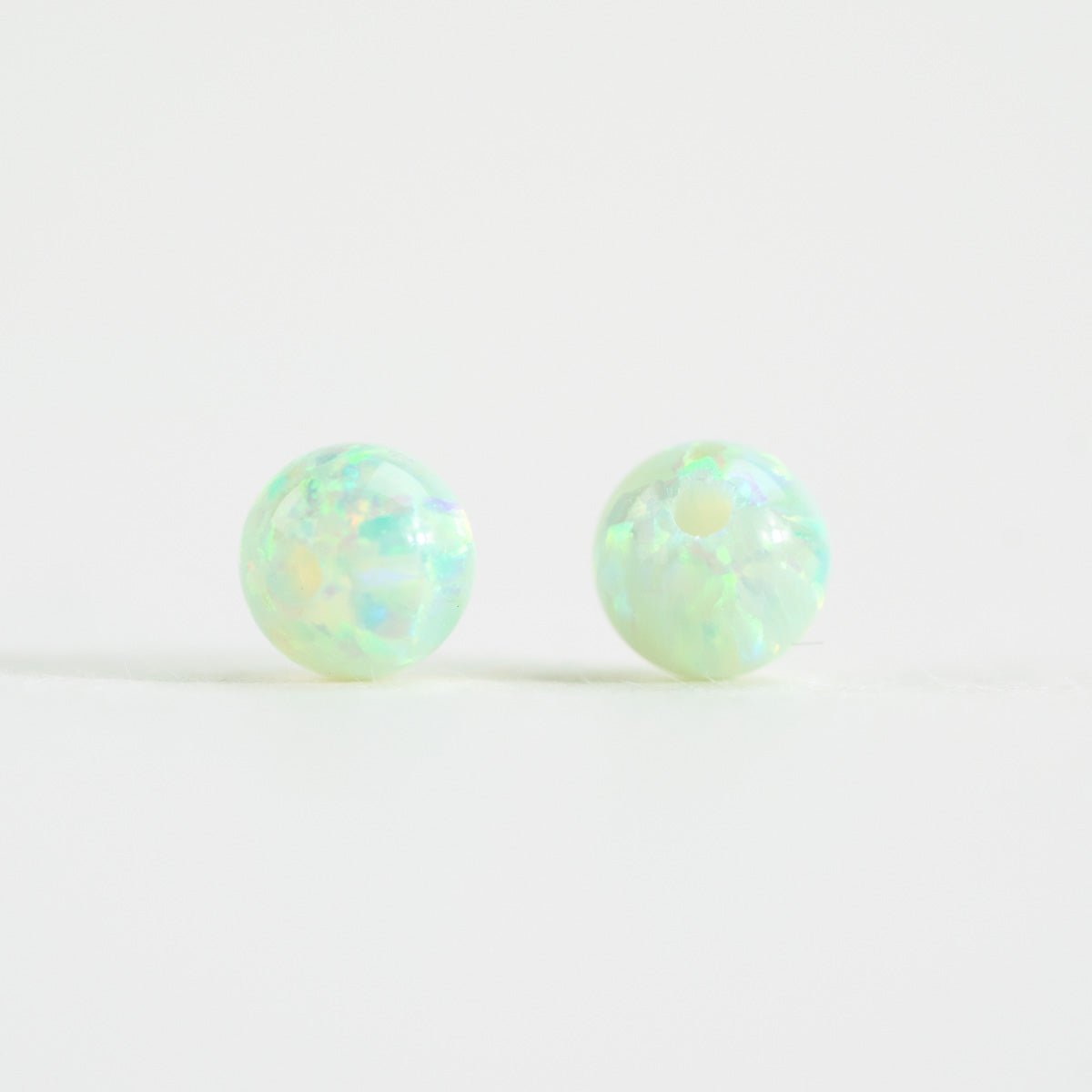 Pair of round opal beads on a light white background