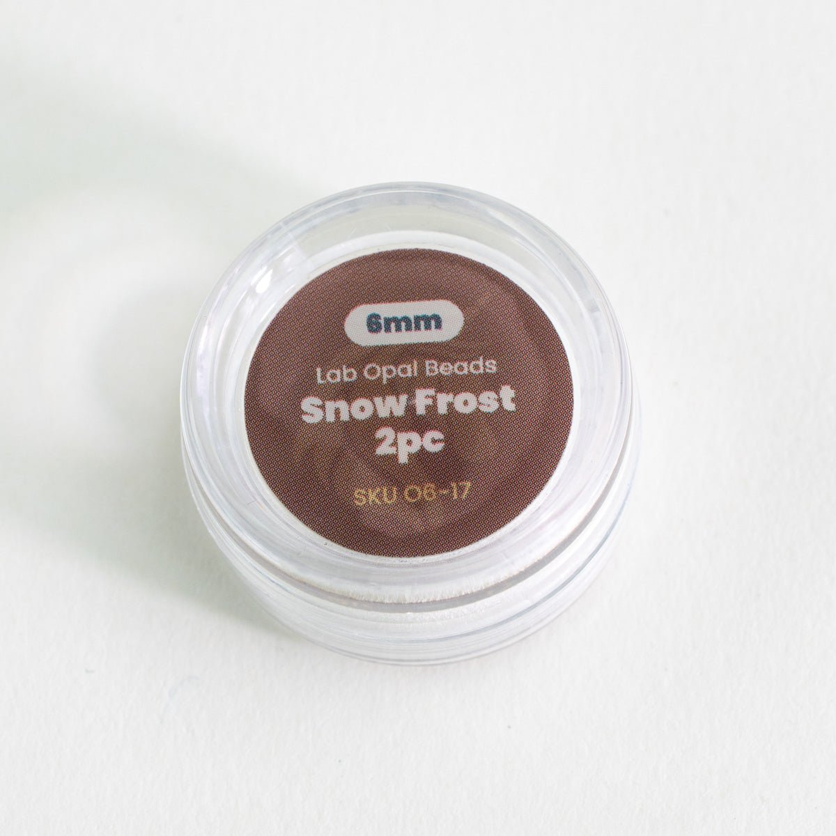 Container of lab opal beads labeled 'Snow Frost 2pc' on a white background