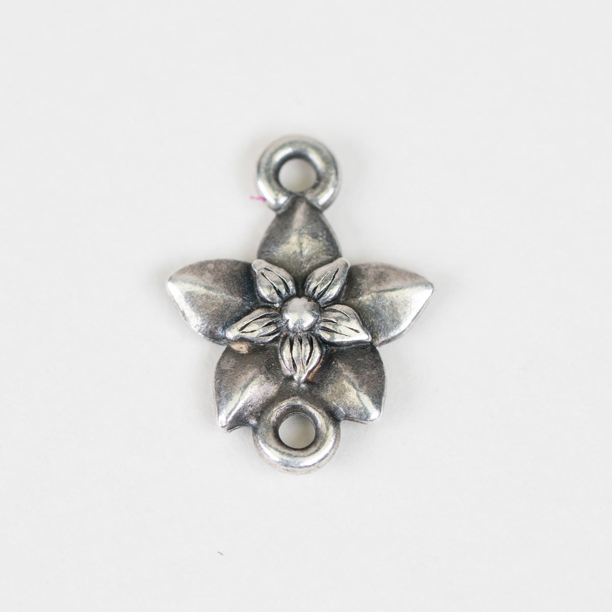 A single silver-toned metal flower charm with two loops, one at the top and one at the bottom, shown on a plain white background.