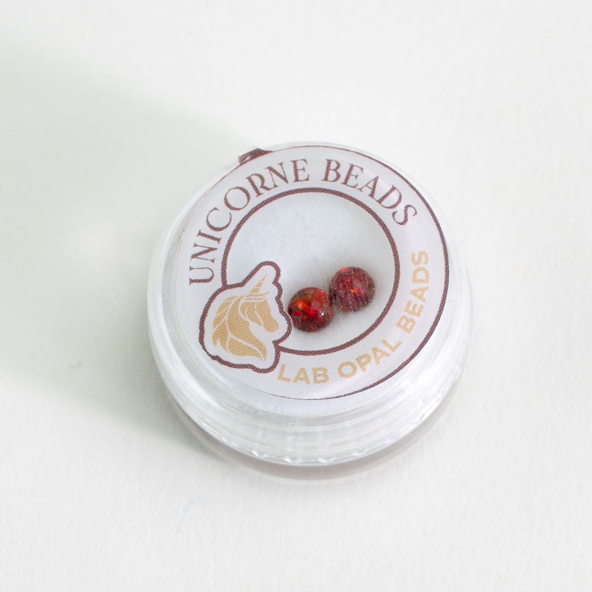 Two red cherry beads in Unicorne Beads packaging
