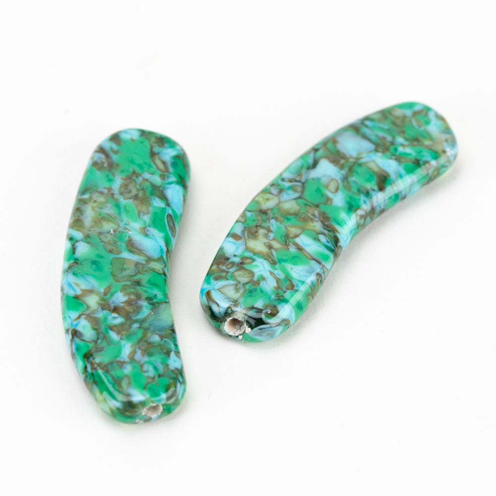 Two flat banana shaped beads with a mixture of color including grass green, ocean blue and brown. Each bead has two holes on each side used by jewelry makers to place on string.