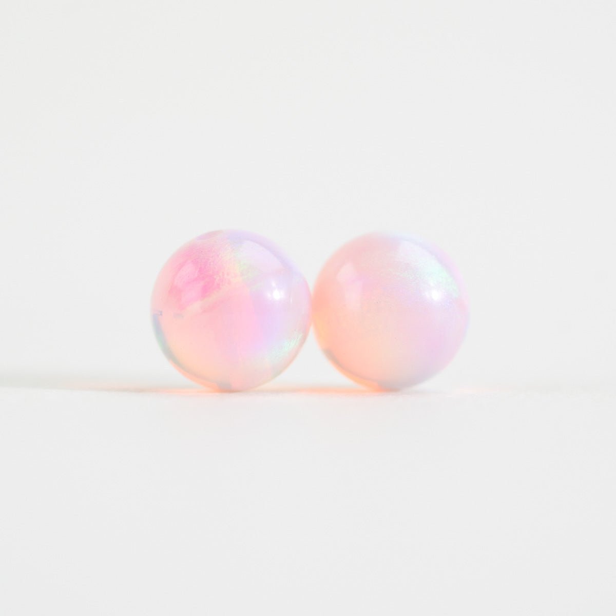 Pair of round, iridescent beads on a light white background