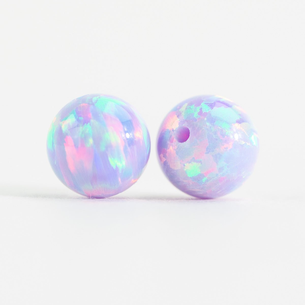 Two round opal beads with colorful iridescent patterns on a white background