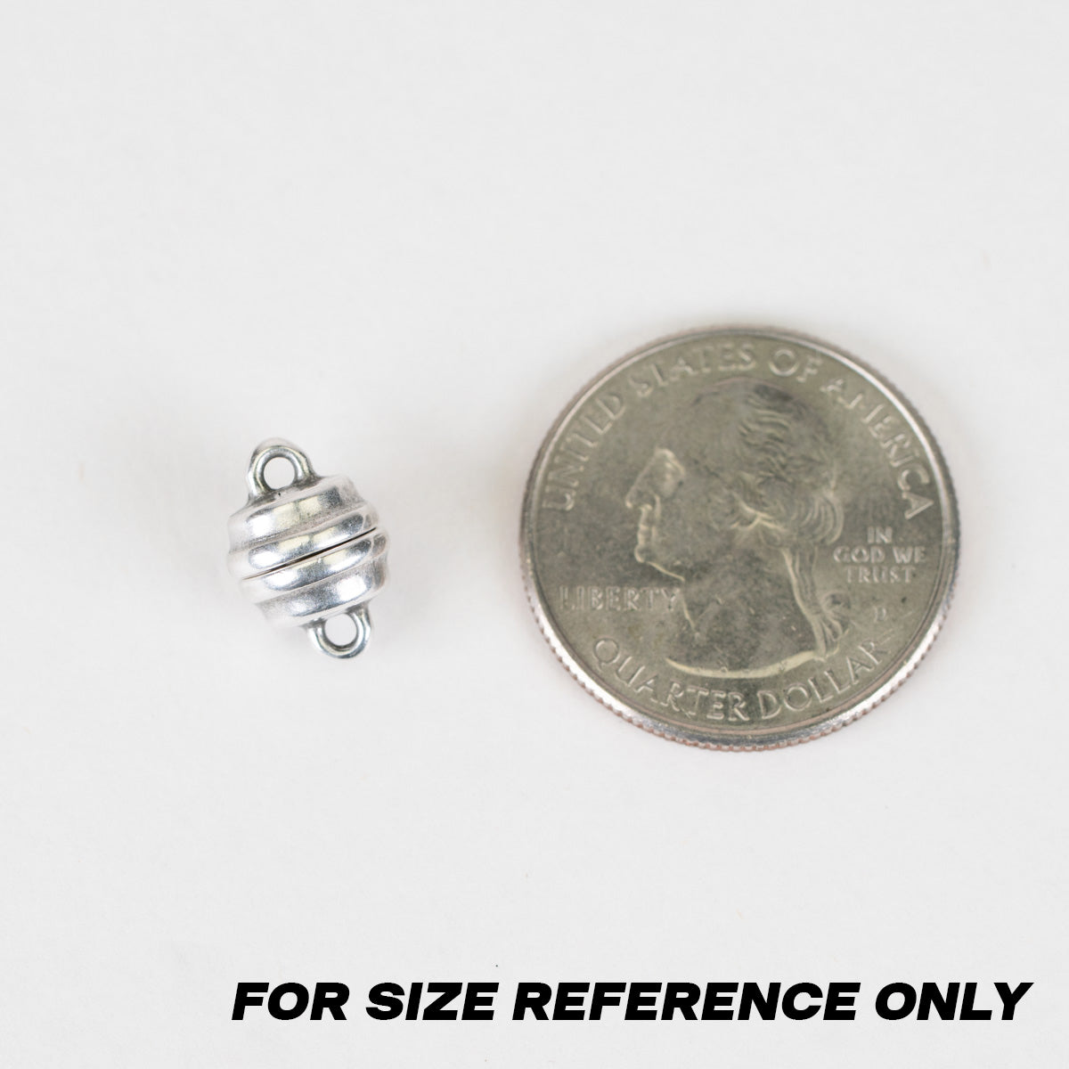 A small silver metal bead or charm shown next to a U.S. quarter