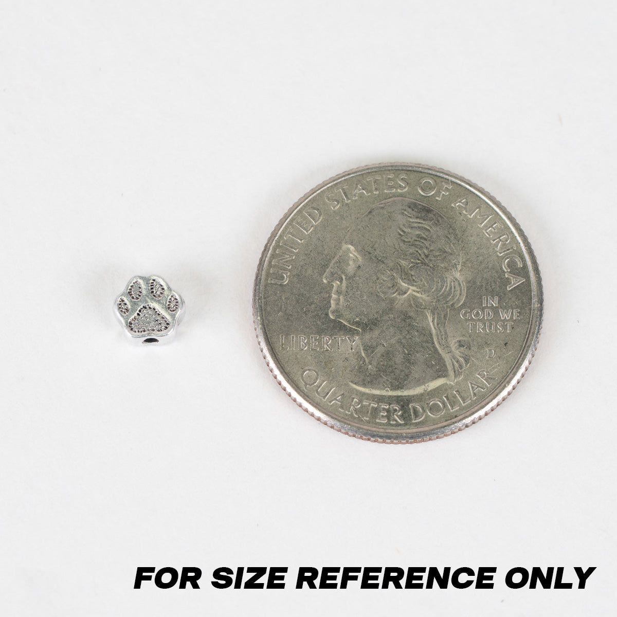 A small silver paw-shaped bead shown next to a U.S. Quarter