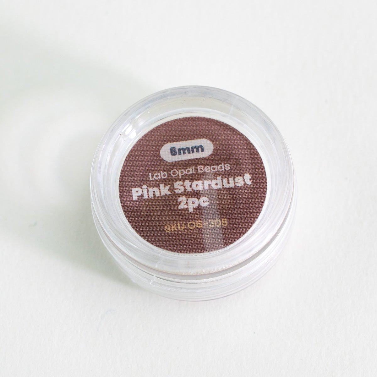 Container of pink opal beads with label on a white background