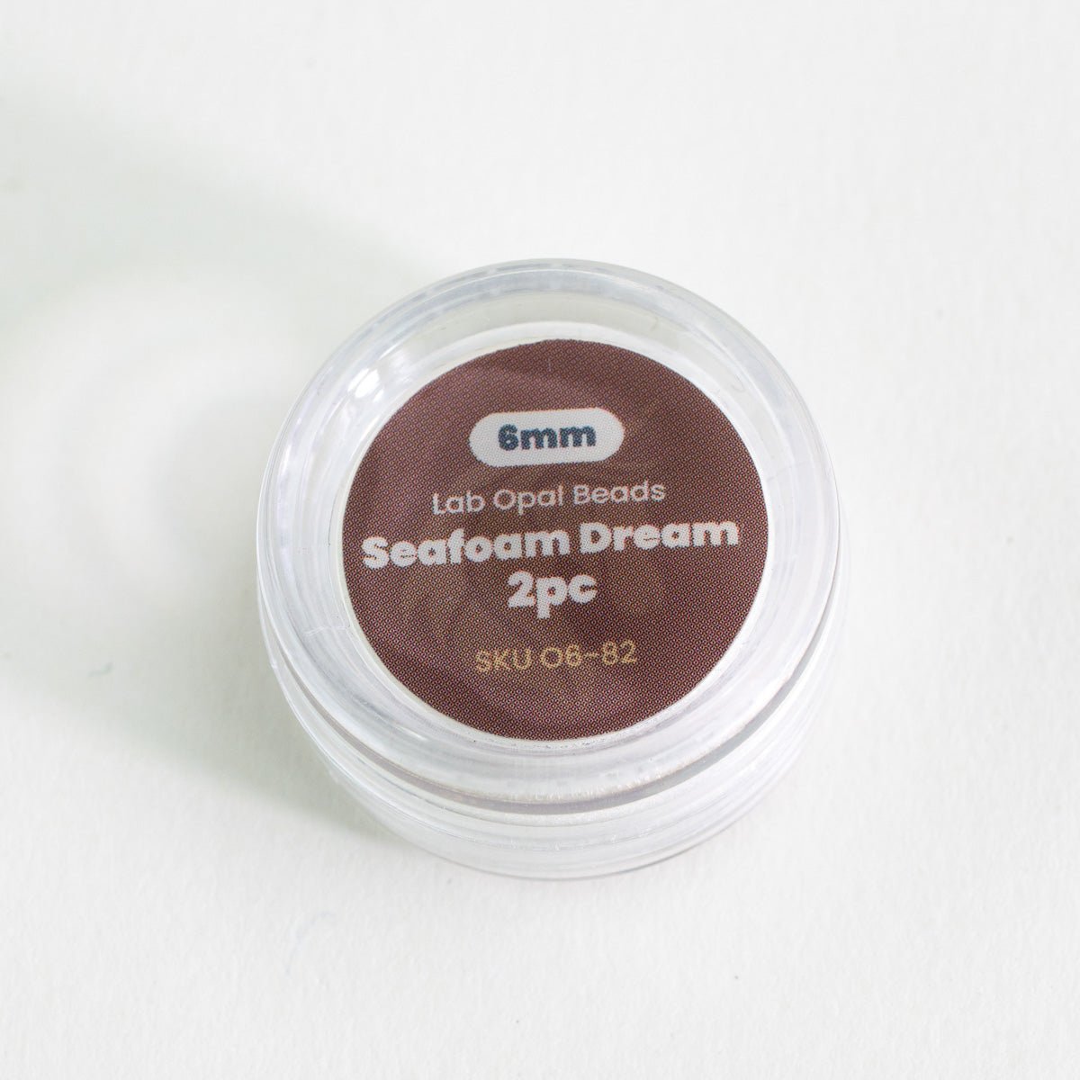 Container of lab opal beads labeled 'Seafoam Dream 2pc' on a white background