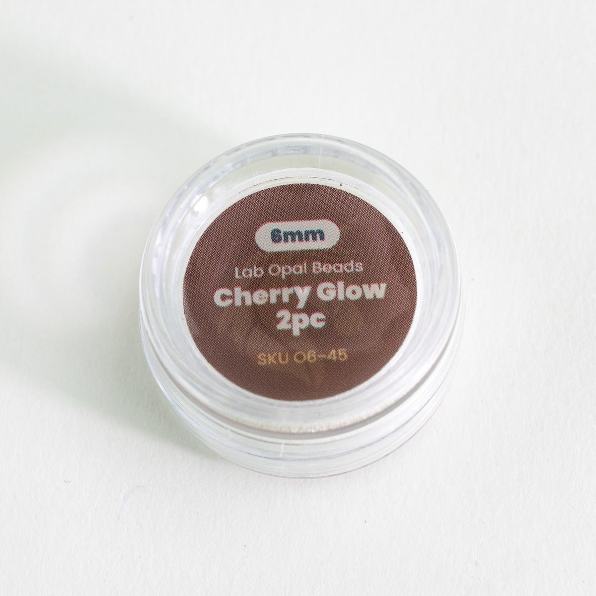 Container of cherry glow beads with a label on a white background