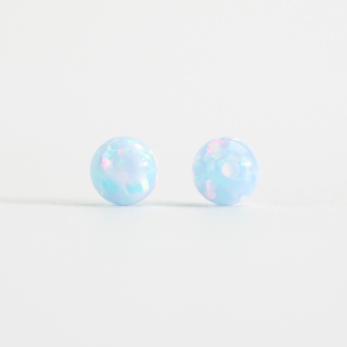 Pair of light blue opal stud beads on a white background