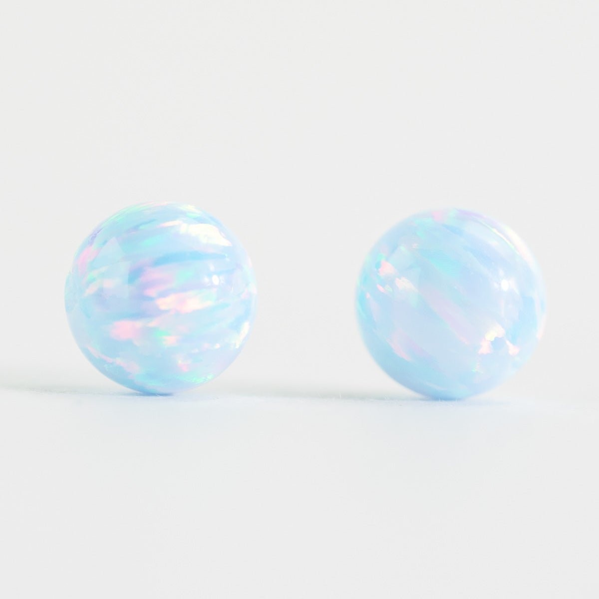 Pair of round opal beads on a light white background