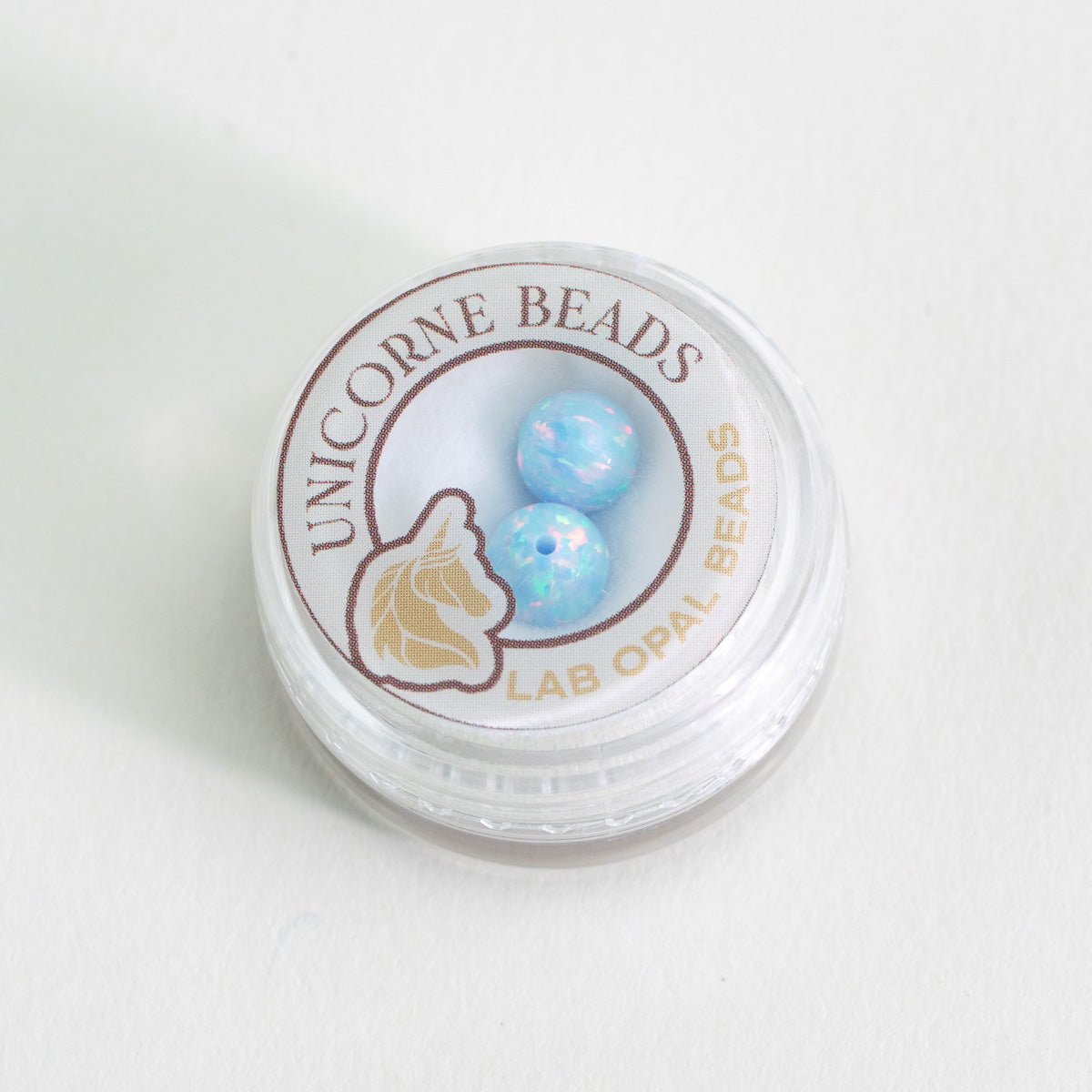 Container of Unicorne Beads with two blue beads on a white background