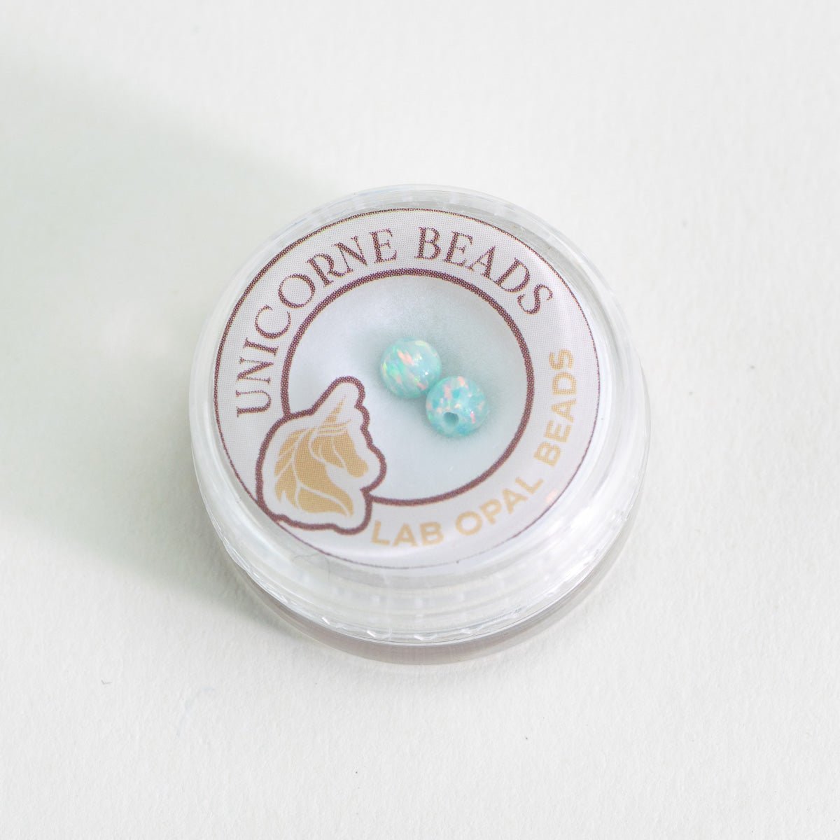 Unicorne Beads container with two turquoise beads on a white background