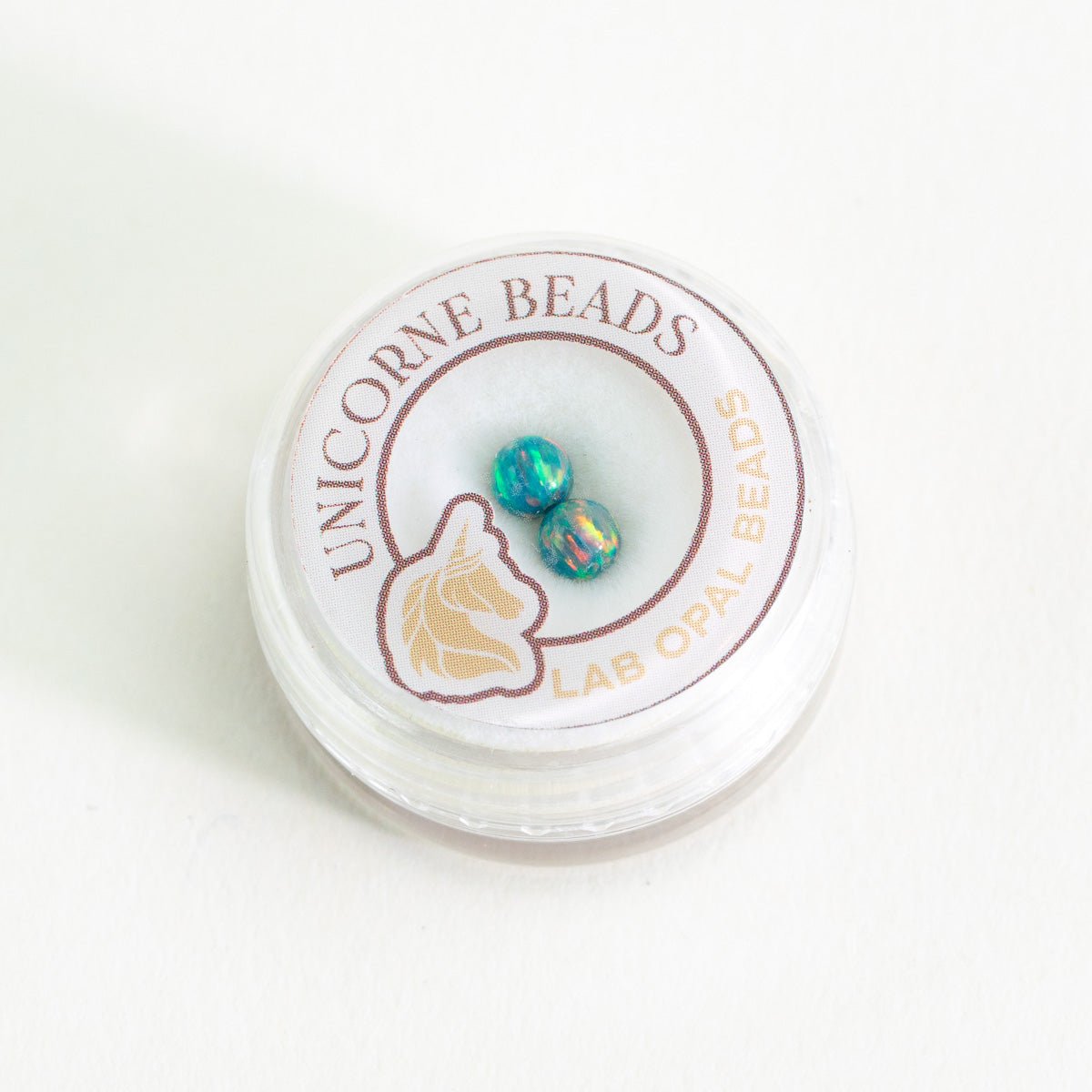 Unicorne Beads container with lab opal beads on a white background
