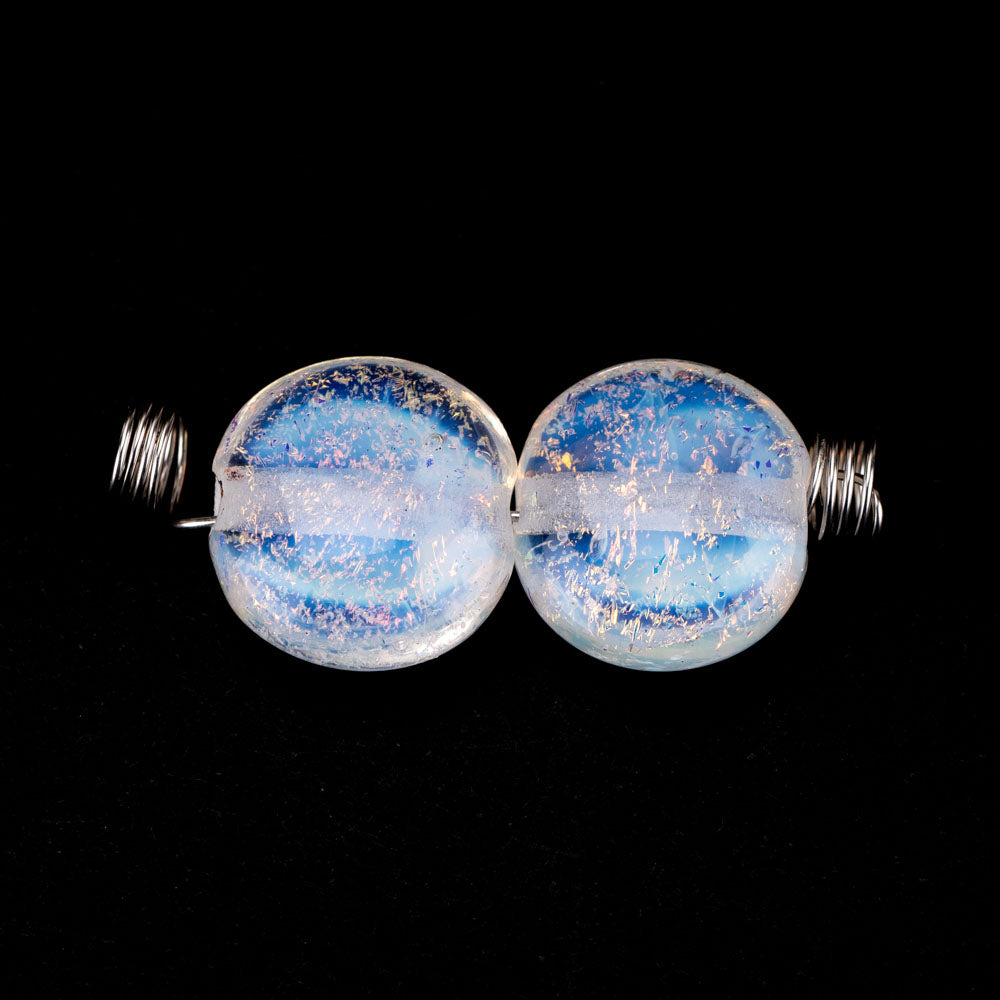 Two glass beads from Unicorne Beads. Beads are light blue with a rainbow shine to them. Each beads has a hollow center to be used for jewelry making. 