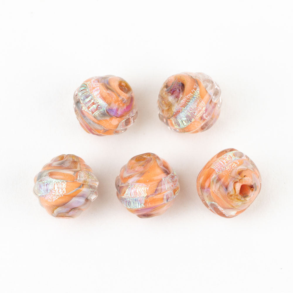 Five individual glass jewelry beads shaped like a coconut. Each glass bead is orange with pints of pink and dichroic foiling. The beads each have hole in them to be used for jewelry making. 