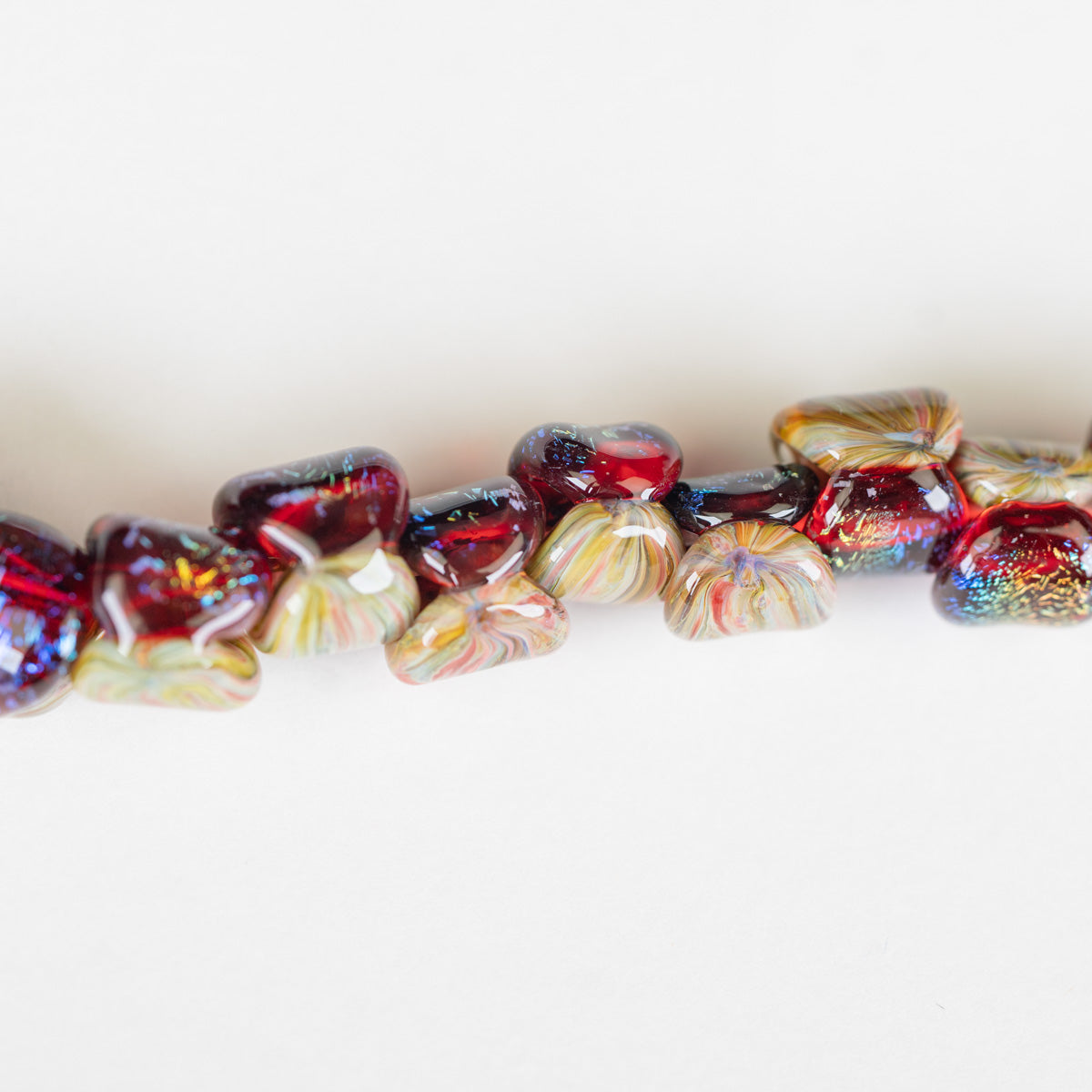 Close-up of a bracelet with red and multicolored glass beads on a white background