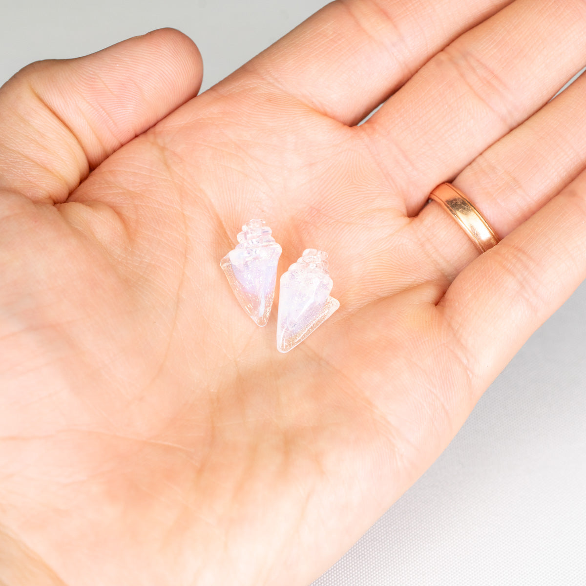 Two small shell-shaped objects on a person's palm with a white background