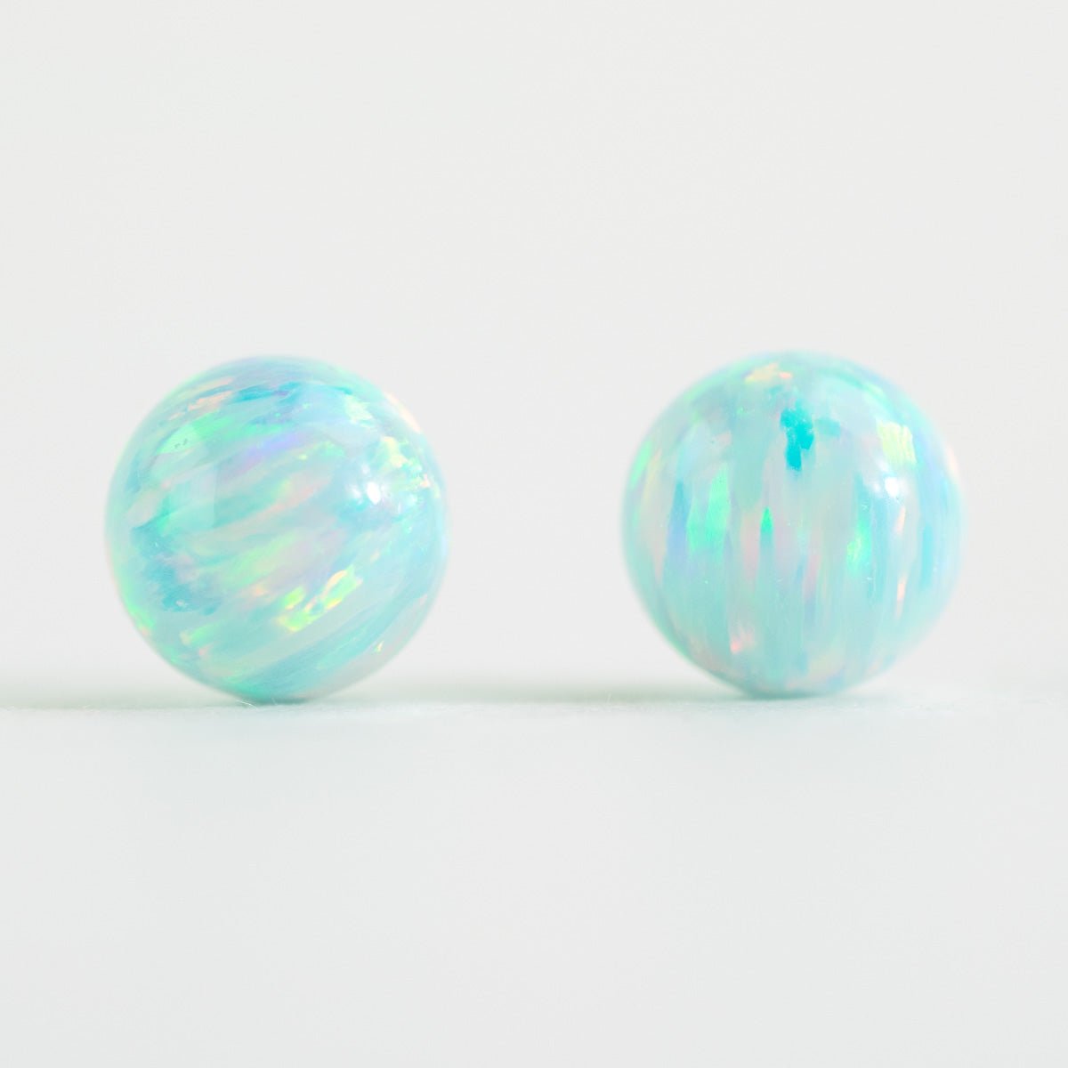 Pair of round opal beads on a light white background