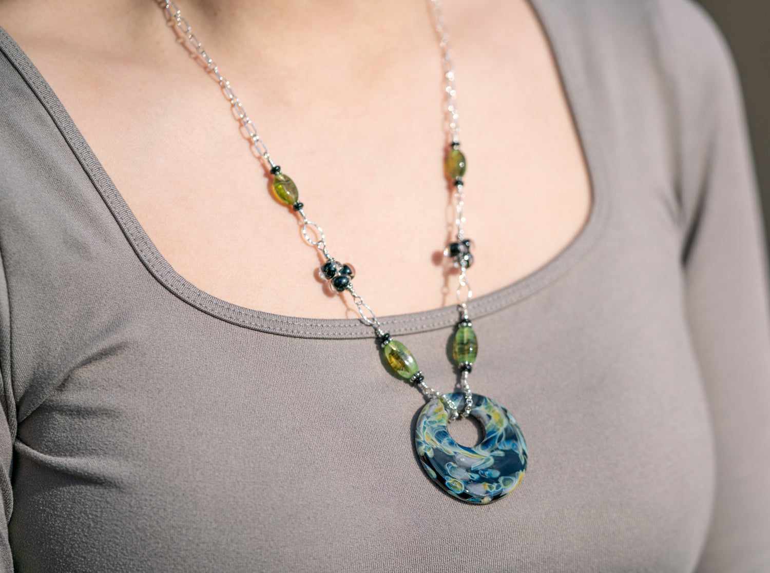 Unicorne Bead's glass halo disk bead crafted into a necklace, displayed on a female