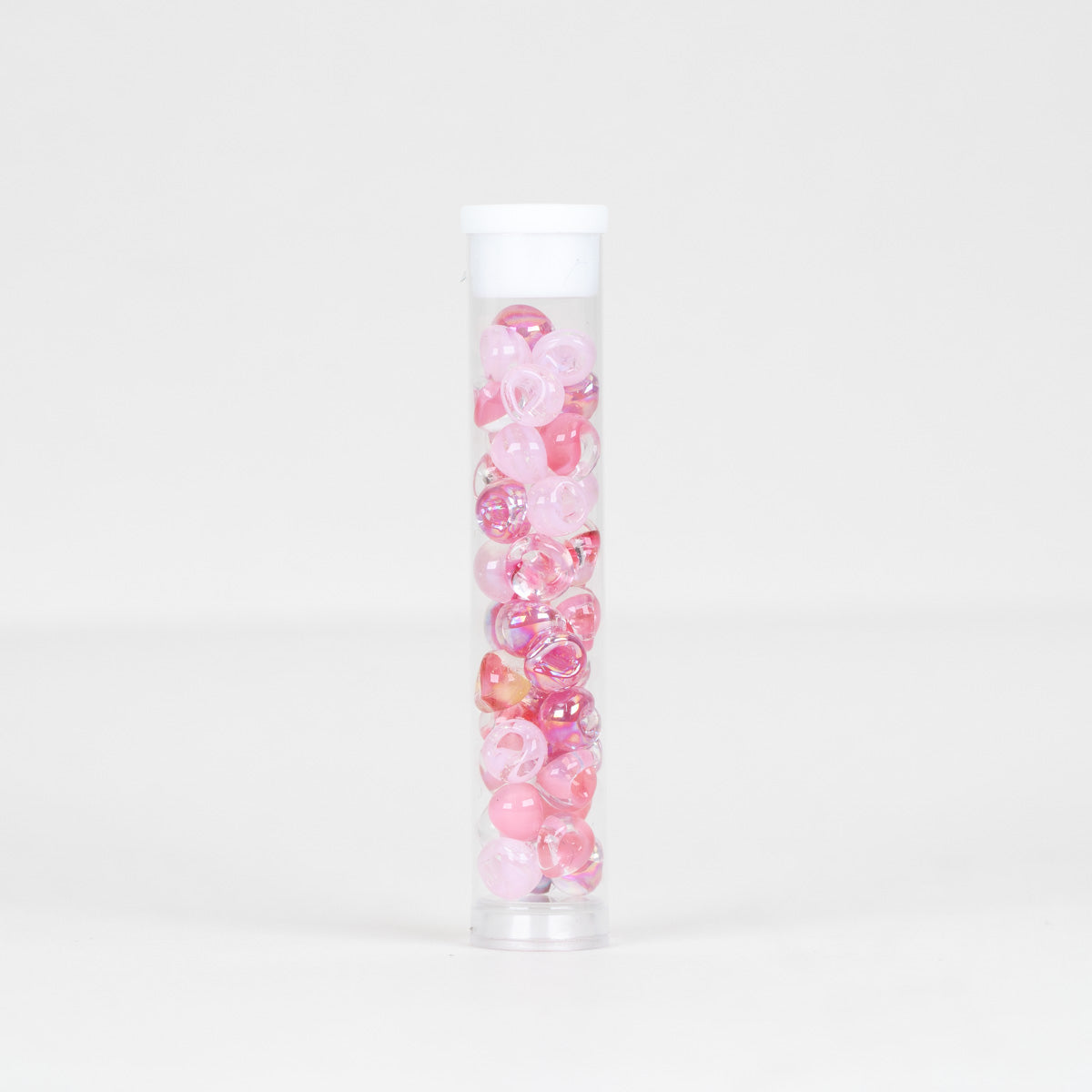 A clear plastic tube with a white screw-on cap, filled with small round pink decorative beads photographed against a clean white studio background.