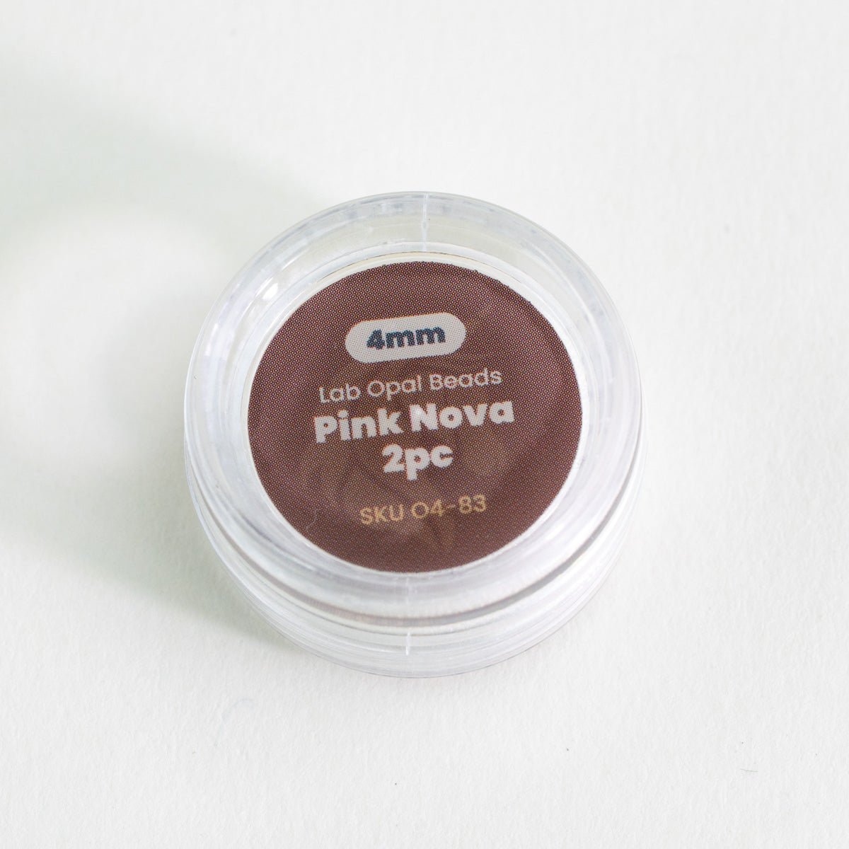 Container of Pink Nova lab opal beads on a white background