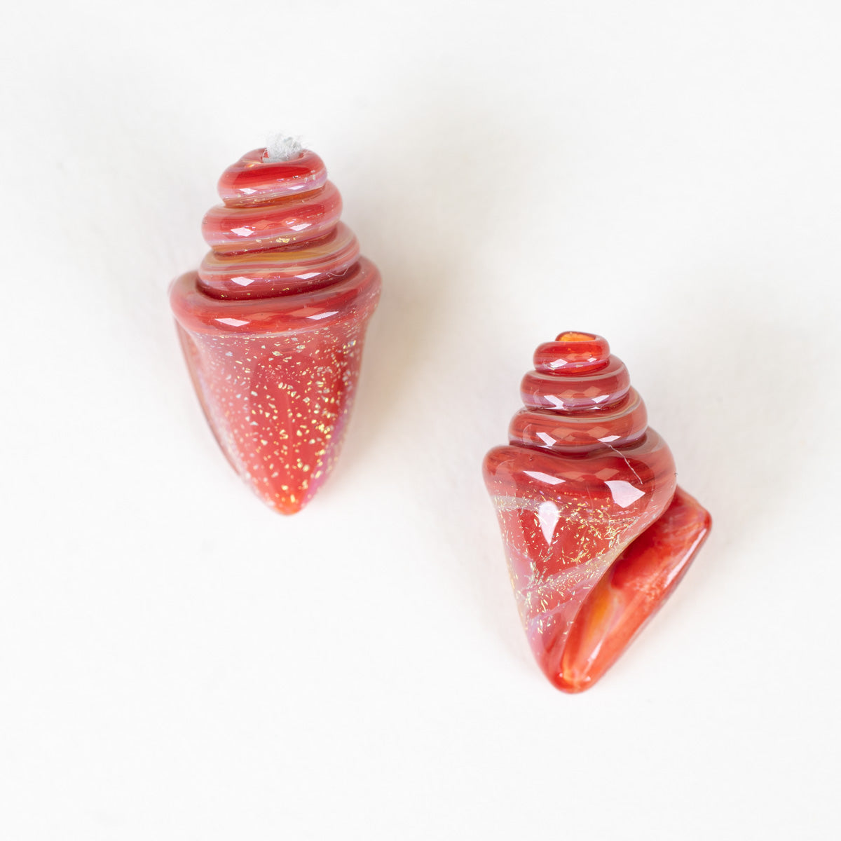 Two red and white striped glass beads on a white background