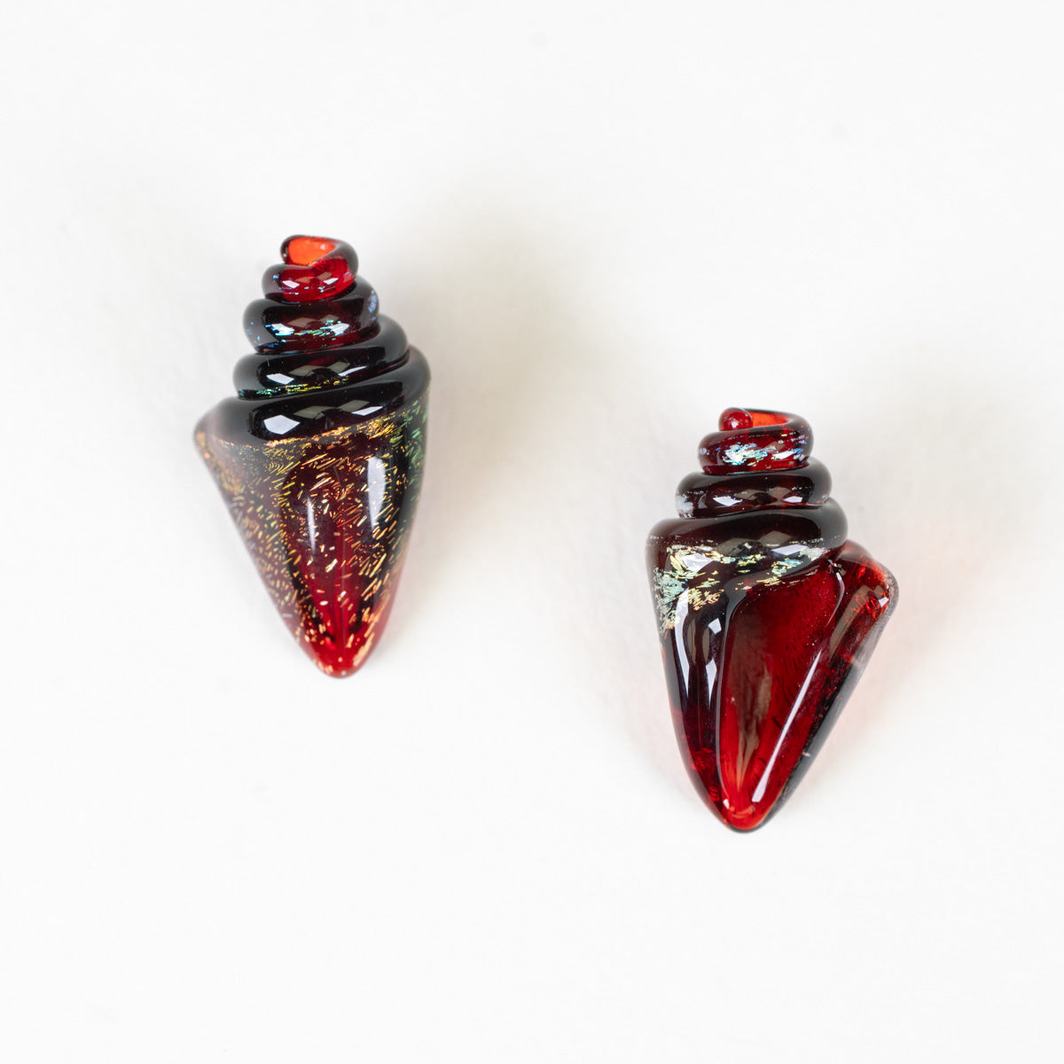 Two red and black glass seashell nobilis beads on a white background