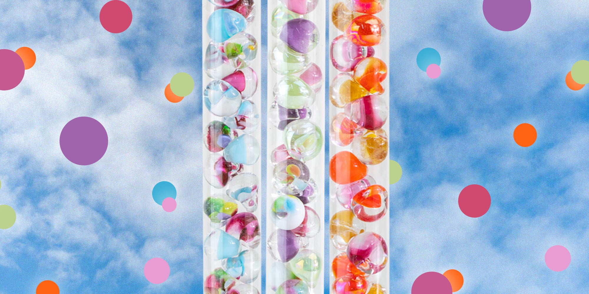 Three tubes filled with glass teardrop shaped beads with cloudy background
