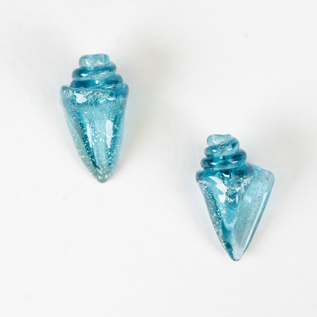 Two blue glass seashell beads with glittery texture on a white background