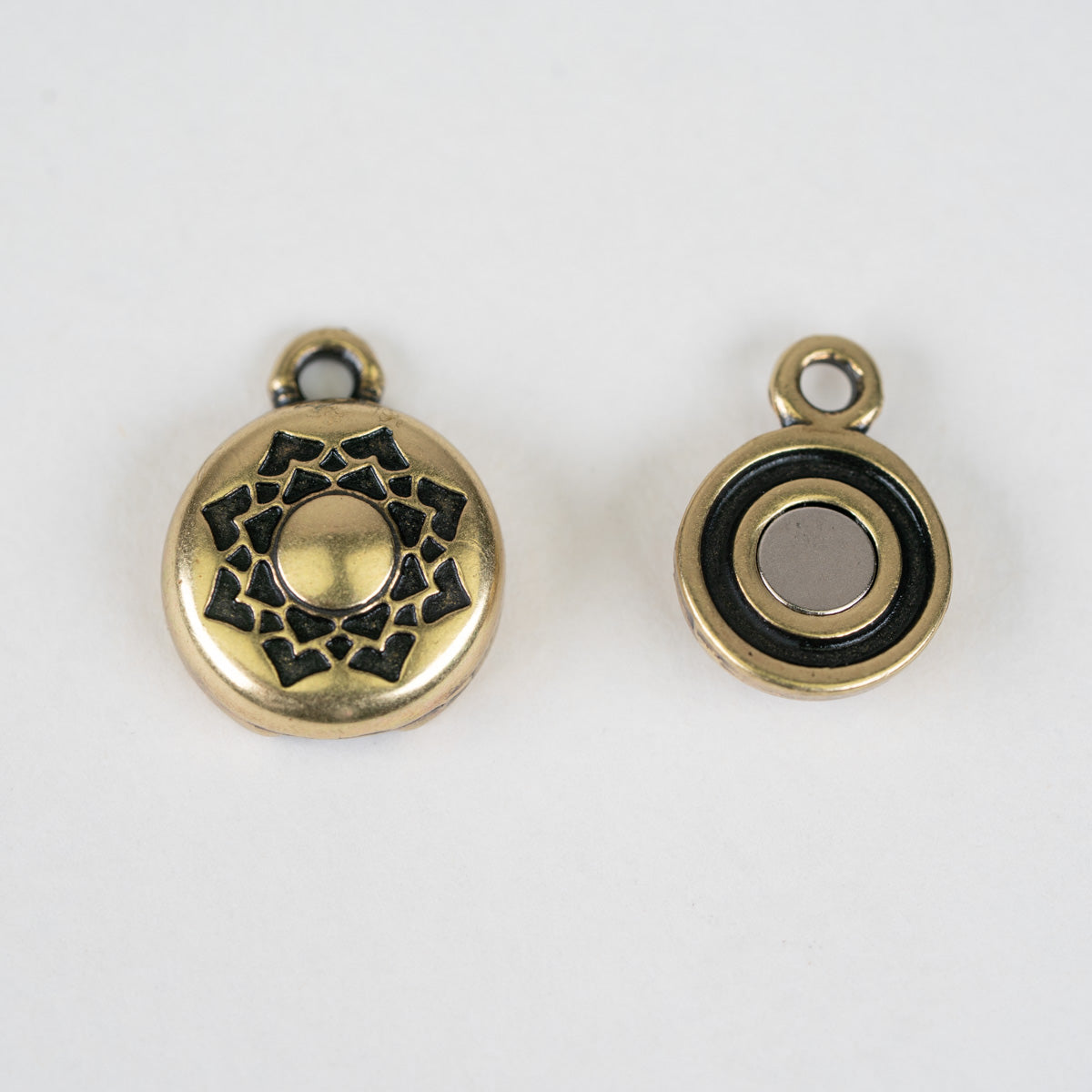 Two antique gold round magnetic button charms with black enamel details, shown from both front and back views on a white background.