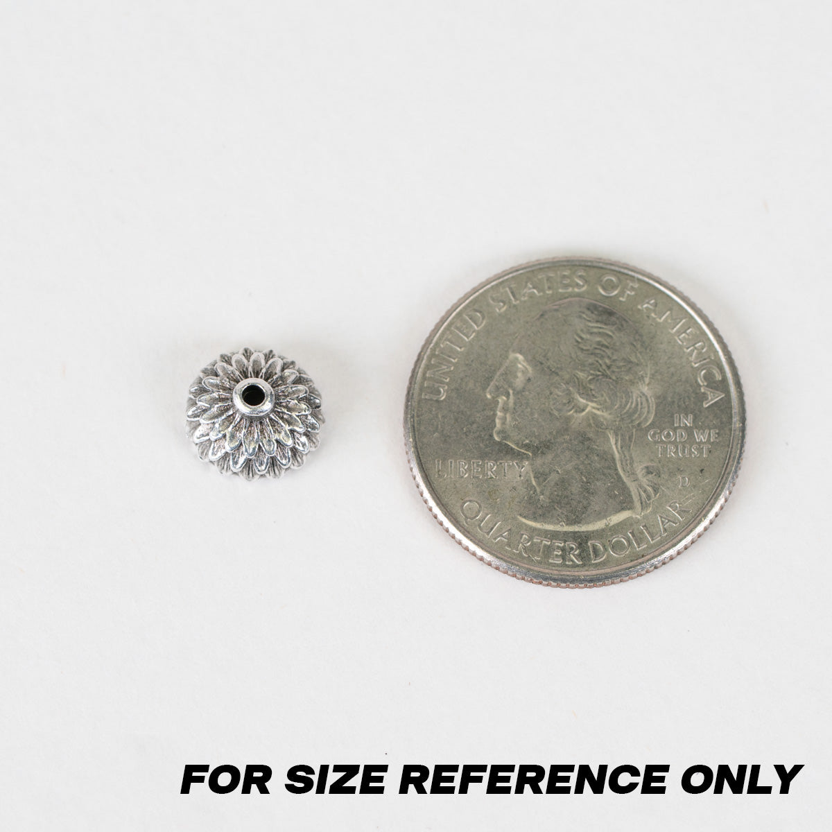 A small silver-toned flower-shaped bead shown next to a U.S. quarter
