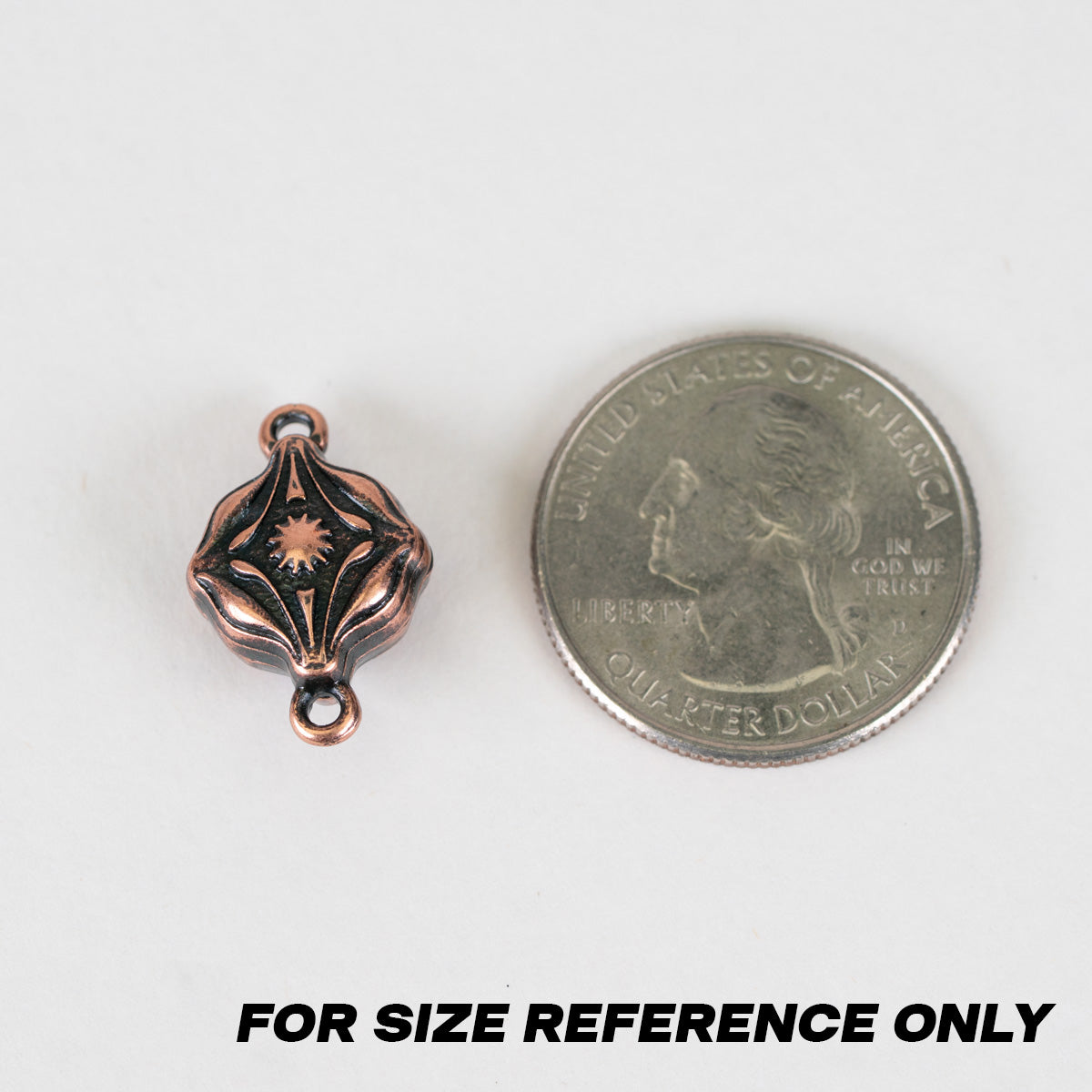 A small metallic charm or bead component shown next to a U.S. quarter