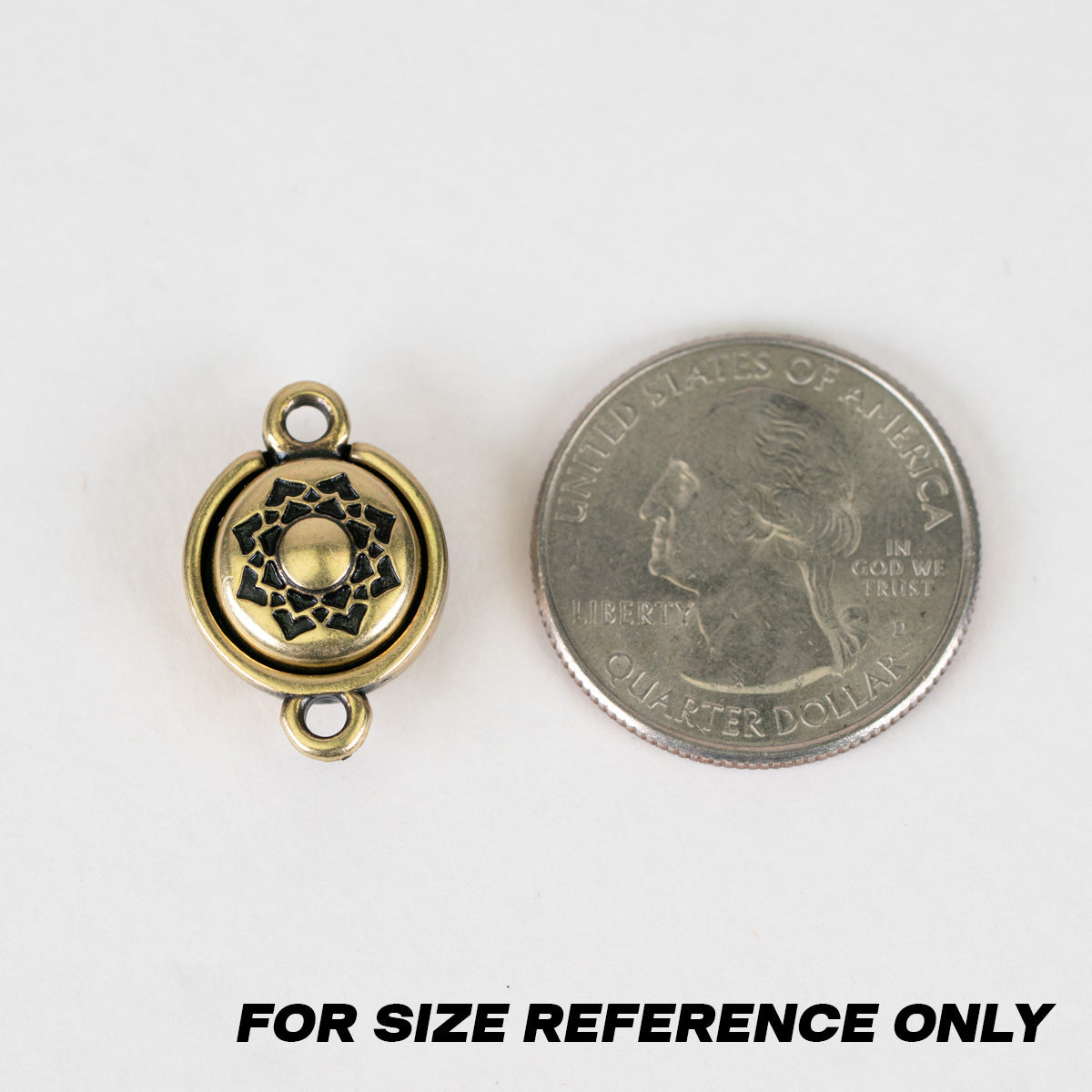 A small round antique gold metal charm with a floral design in the center and loops at the top and bottom, shown next to a US quarter coin for size reference on a white background with the text 'FOR SIZE REFERENCE ONLY' at the bottom.