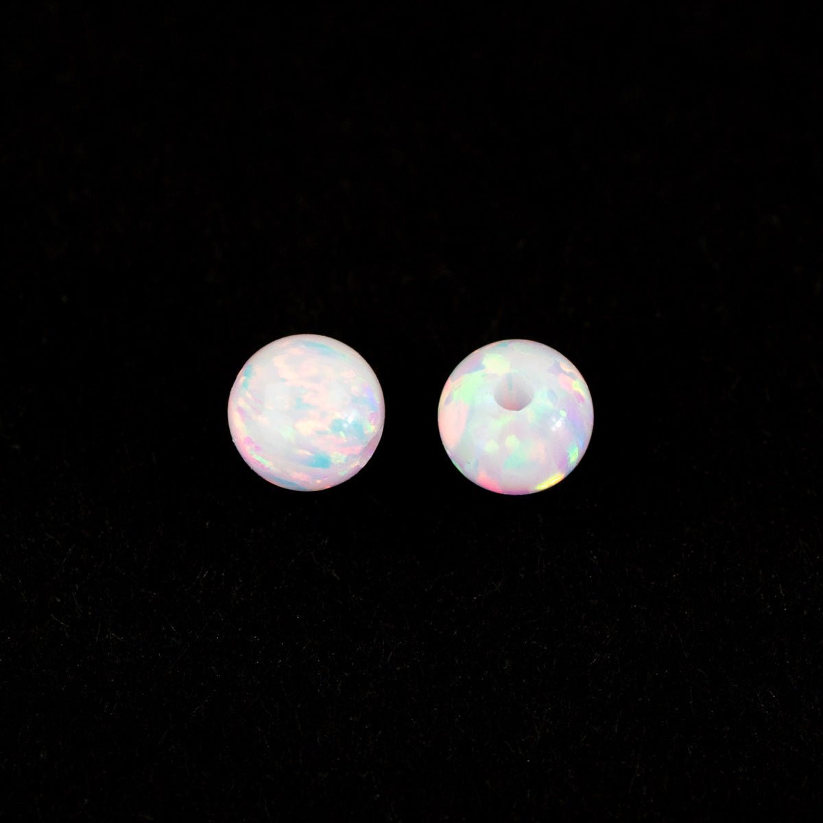 Pair of round, iridescent beads on a black background