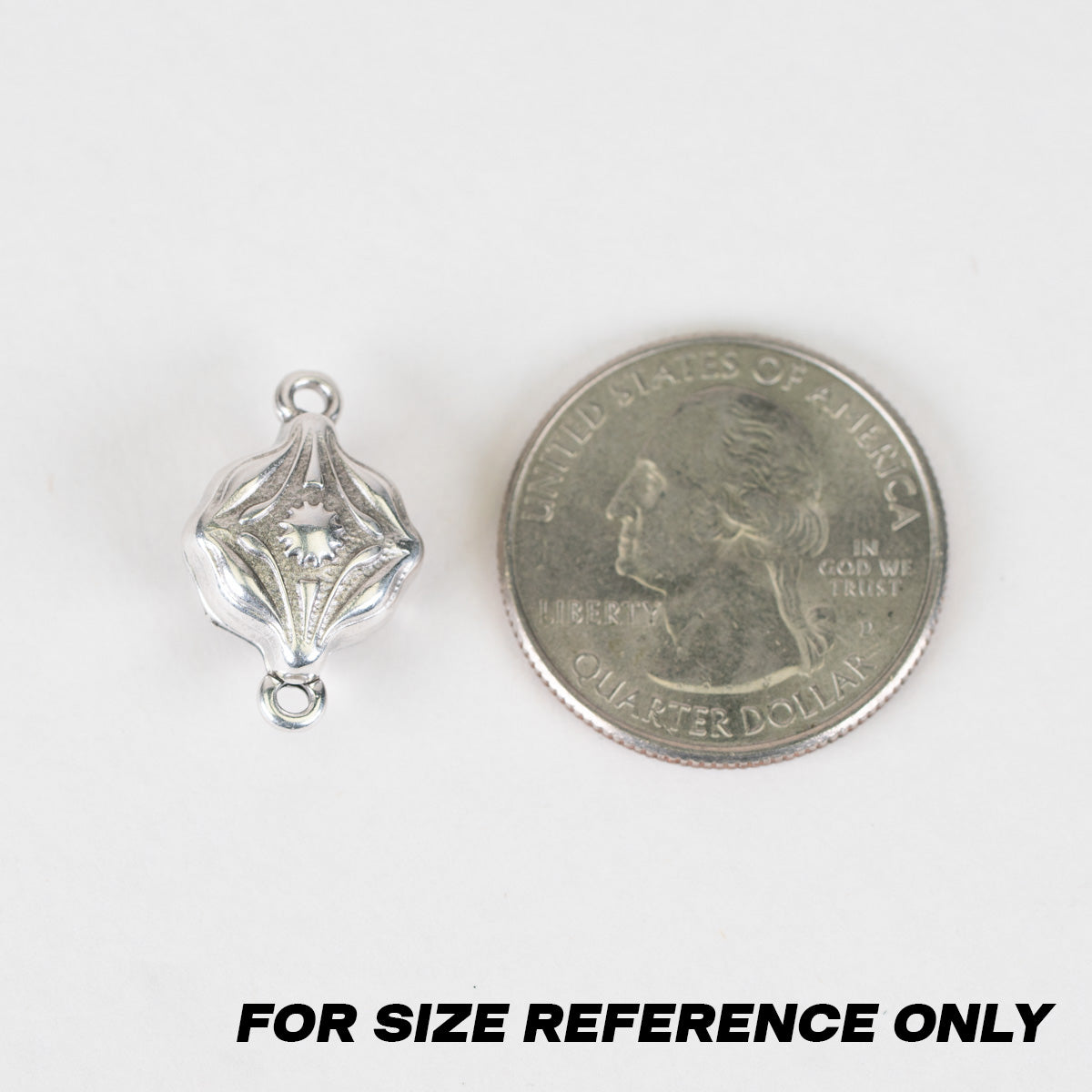 A small silver-toned decorative bead/charm shown next to a U.S. quarter