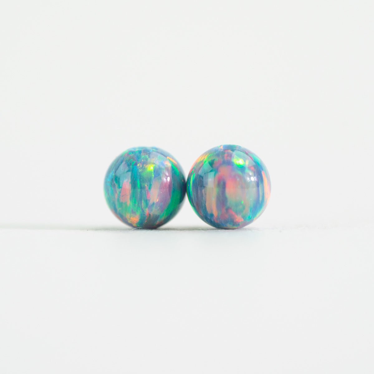 Pair of opal stud beads on a white background