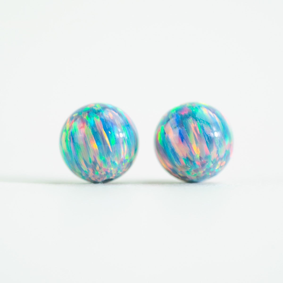 Pair of colorful opal stud beads on a white background