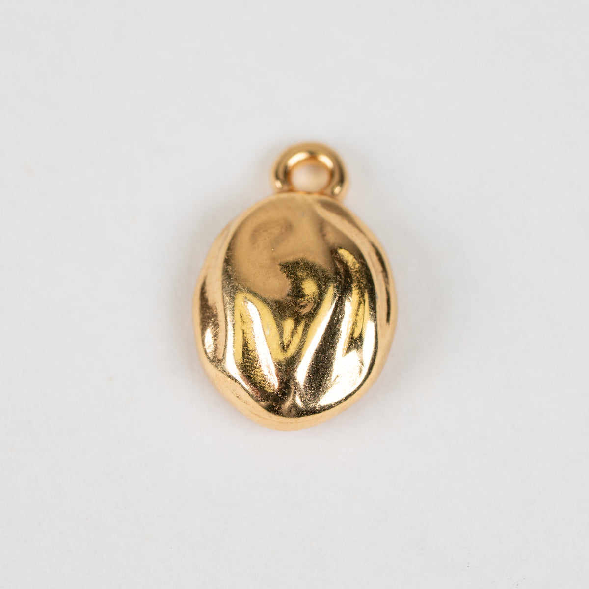 A small oval gold pendant charm with a textured, organic surface and a top loop, shown on a plain light gray background.