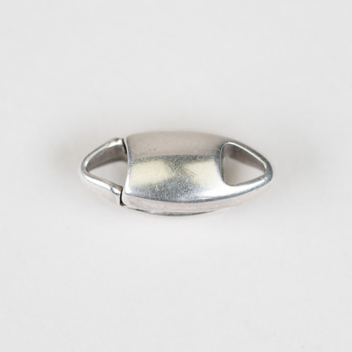 A small oval metal clasp or connector with a brushed silver finish, photographed on a plain light background.