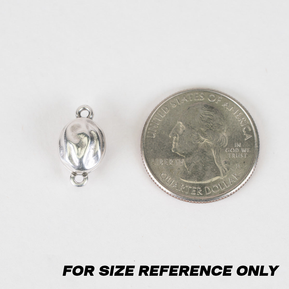 A small silver bead or charm with two loops, shown next to a U.S. quarter