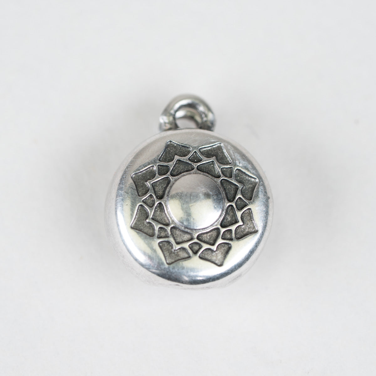 A round silver-toned metal charm featuring a lotus flower design with a central circular cutout and a small hanging loop at the top, shown on a plain white background.