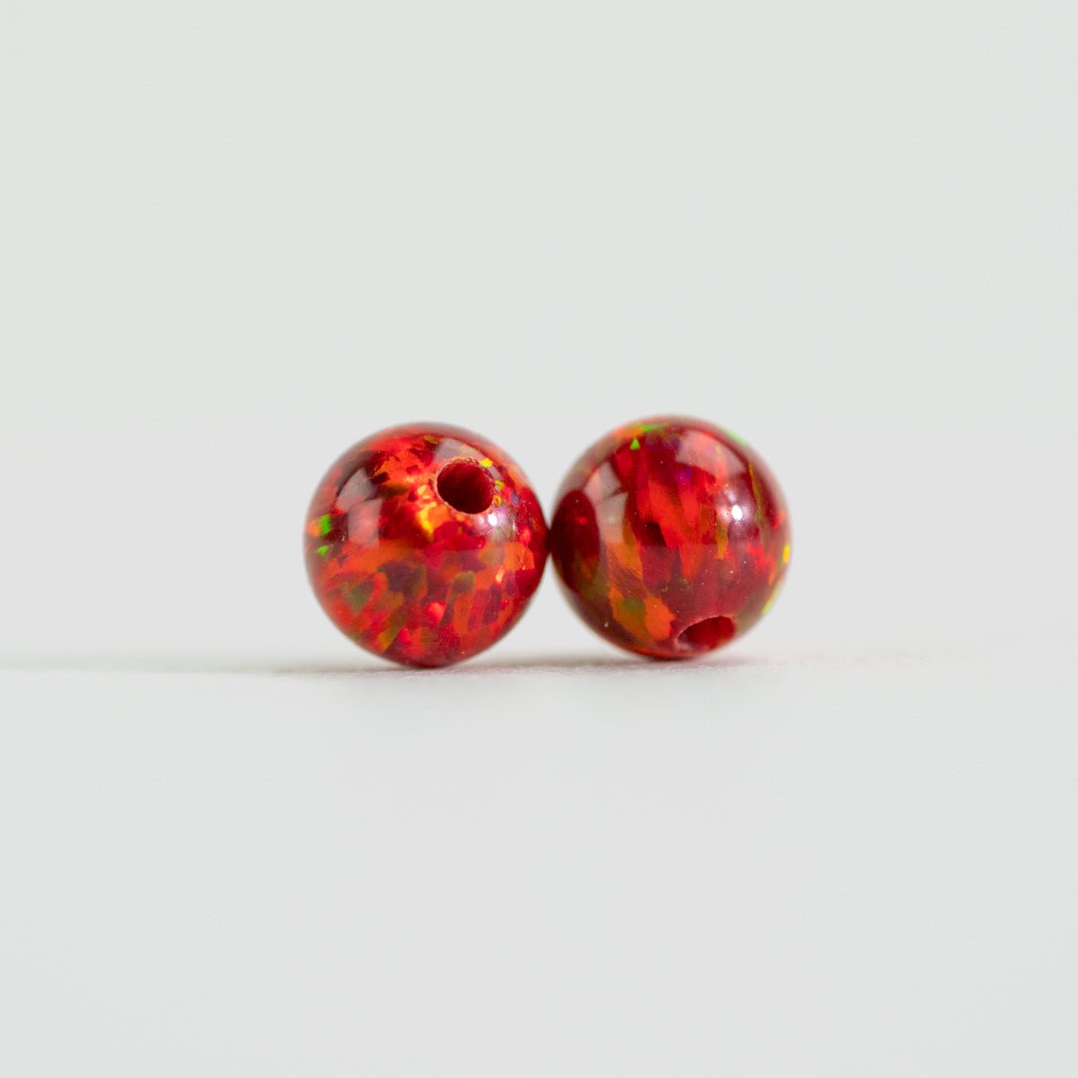 Two bright red mini beads on white background