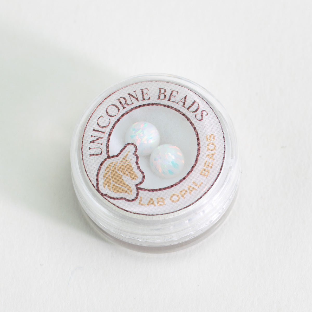 Unicorne Beads container with lab opal beads on a white background