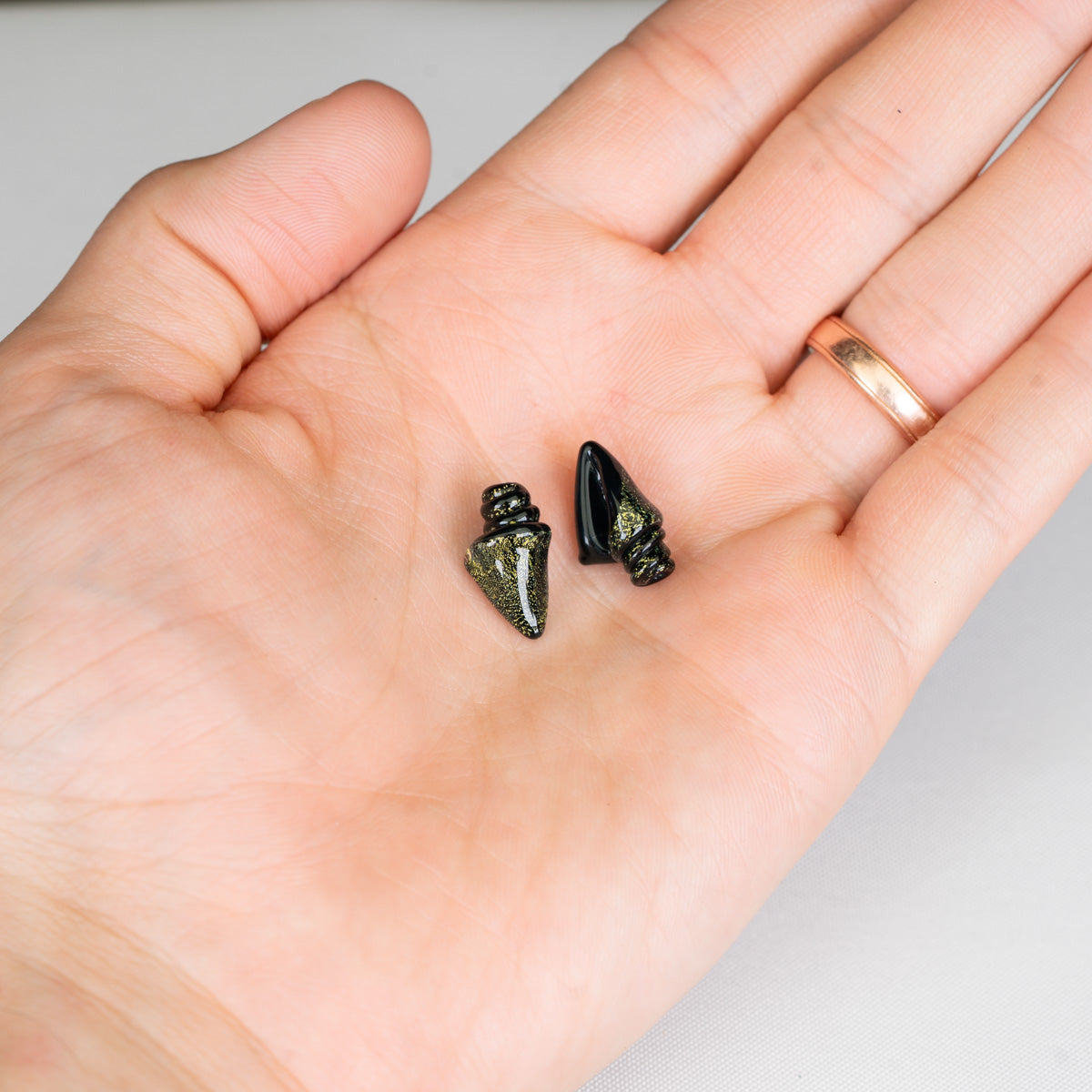 Two small black beads on a person's palm with a white background